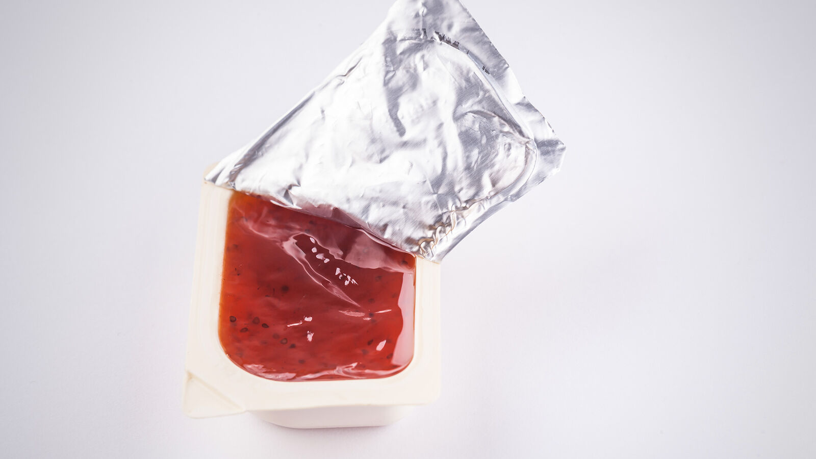 Eine geöffnete Mini-Portion Marmelade in Kunststoffverpackung