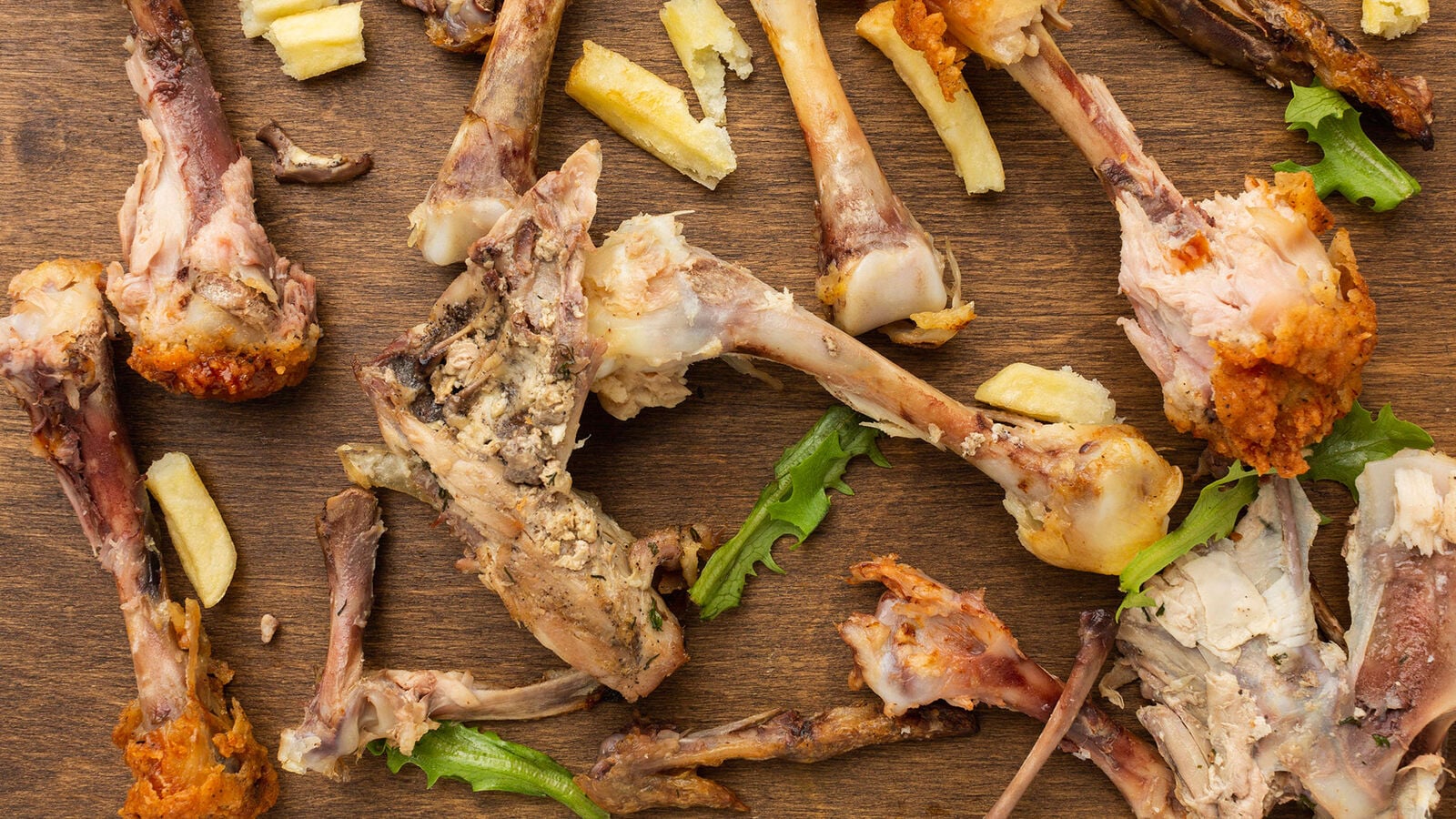 This food waste is unavoidable! Several chewed chicken wings lie on a wooden cutting board